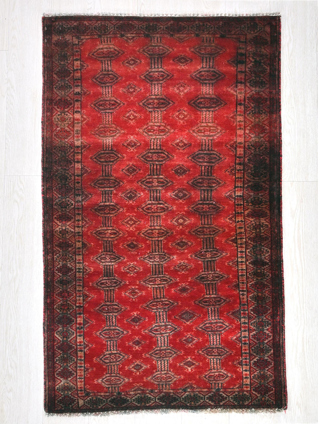 a red and black rug on a white floor