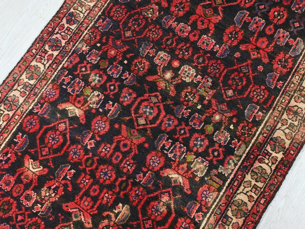 a red and black oriental rug on a white floor