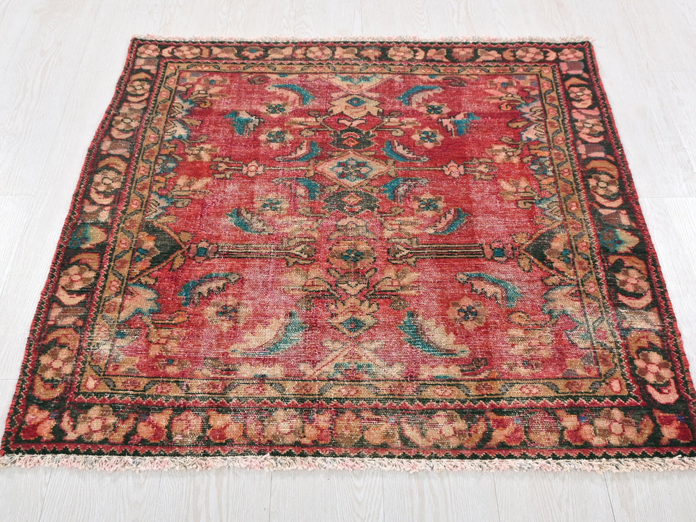 a red rug with a floral design on a white floor