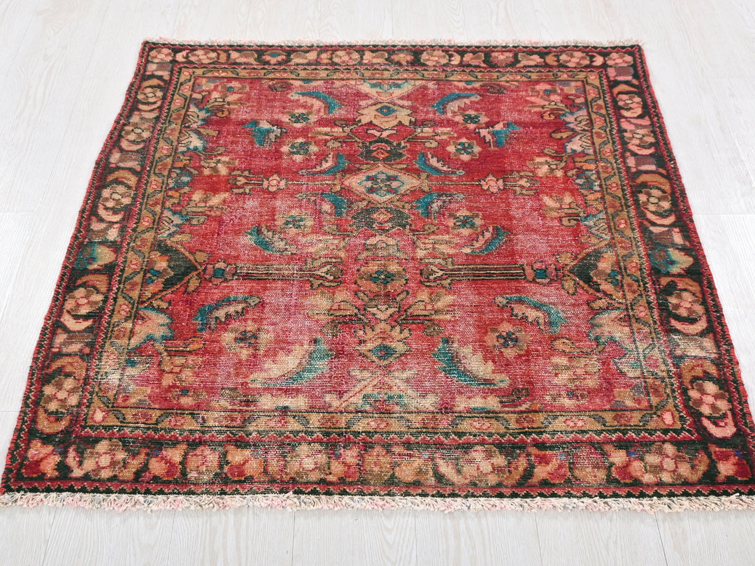 a red rug with a floral design on a white floor