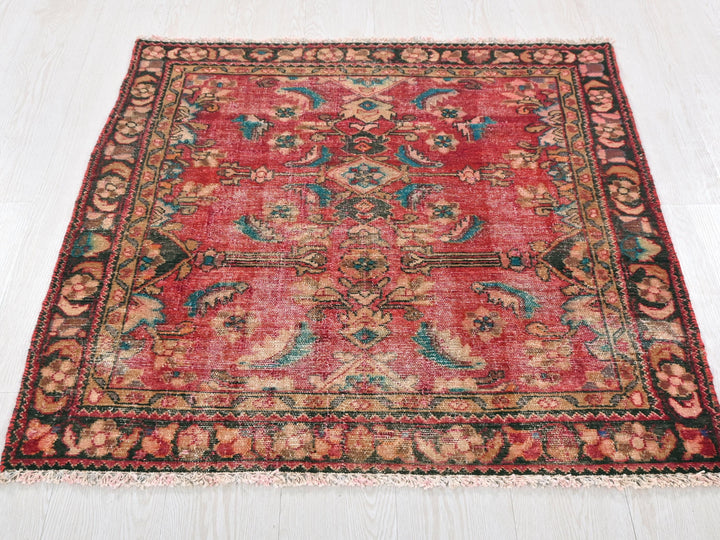a red rug with a floral design on a white floor