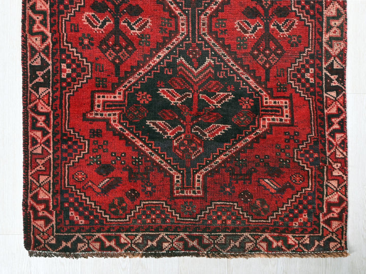 a red and black oriental rug on a white floor