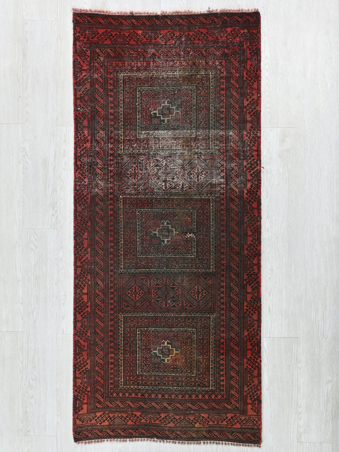a red and black rug on a white floor