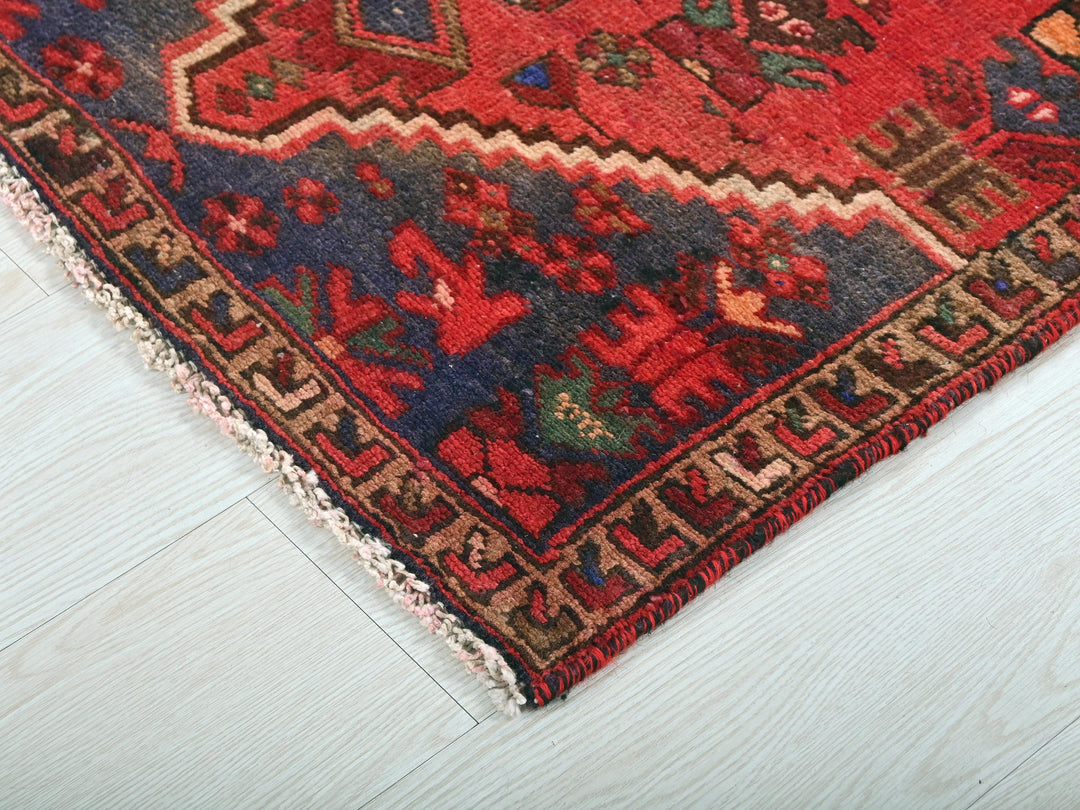 a red oriental rug on a white wooden floor
