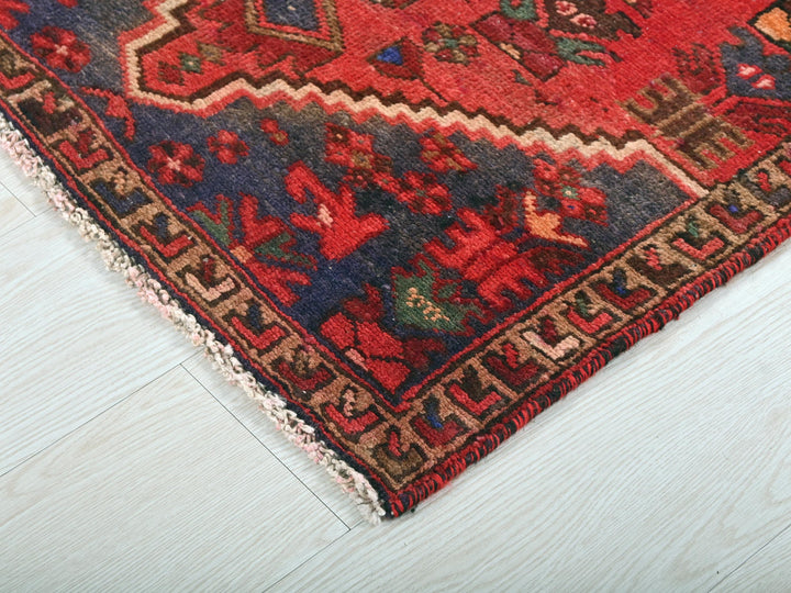 a red oriental rug on a white wooden floor