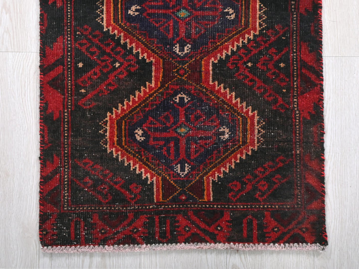 a red, black, and blue rug on a wooden floor