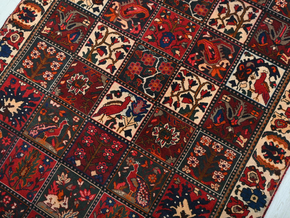 a red and blue rug with a pattern of birds and flowers