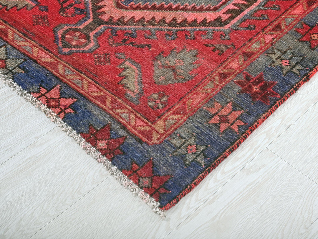 a red, blue, and black oriental rug on a white floor