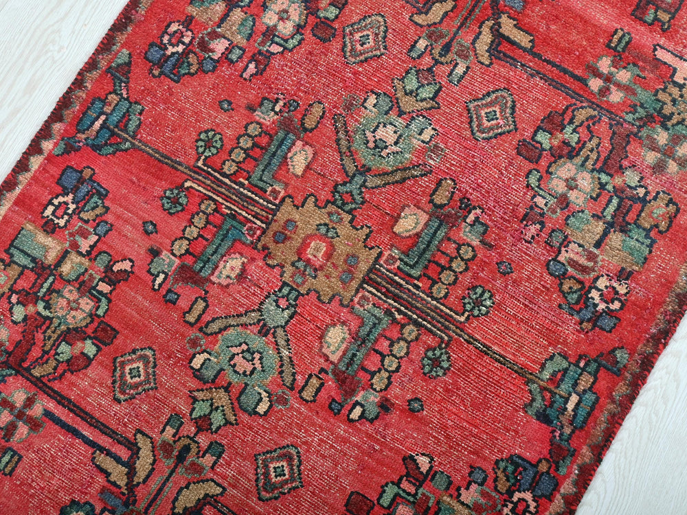 a red oriental rug on a white wooden floor