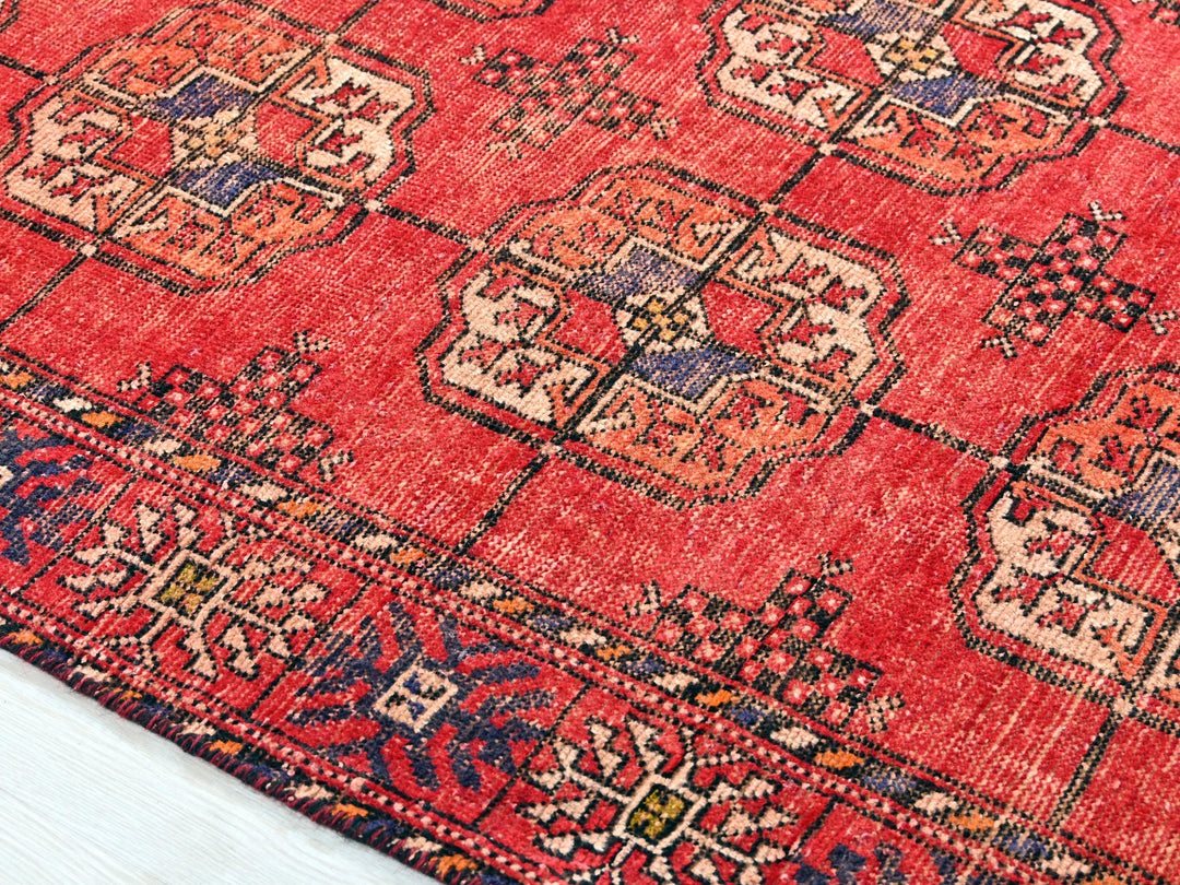 a red oriental rug on a white wooden floor