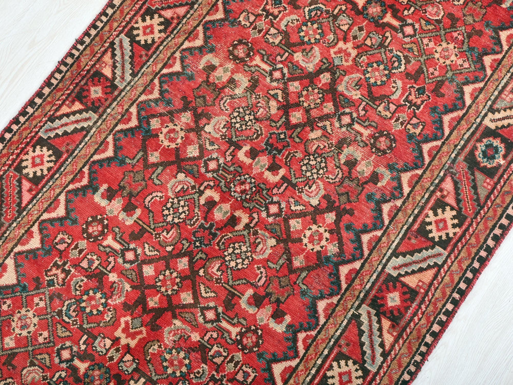 a red and black oriental rug on a white floor