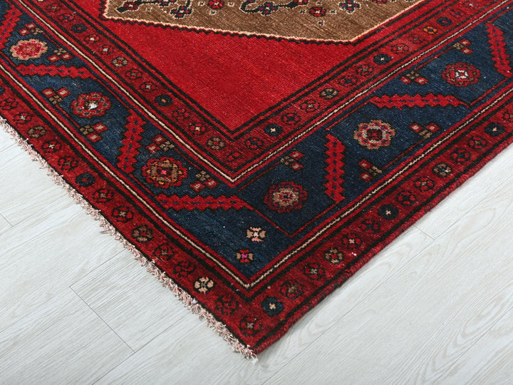a red rug with a gold border on a white floor