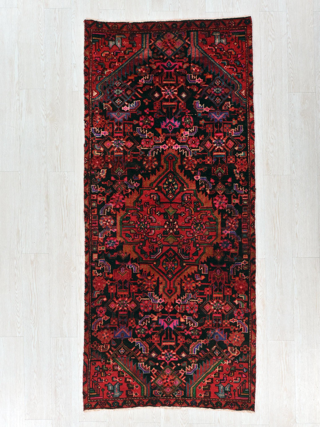 a red and black rug on a white floor