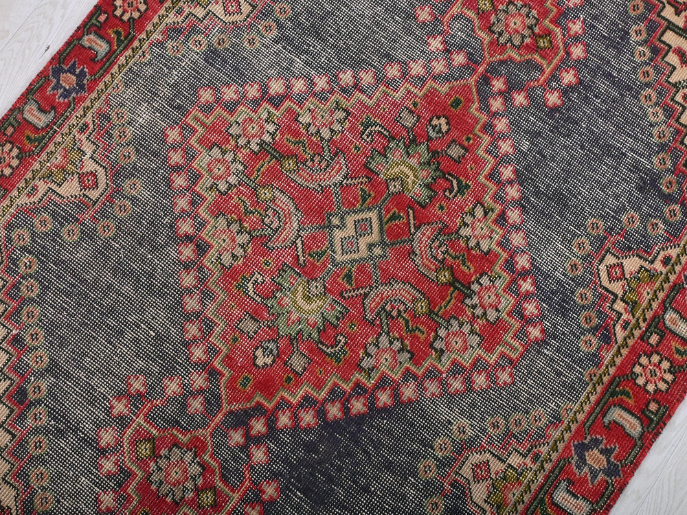 a red and blue oriental rug on a white floor