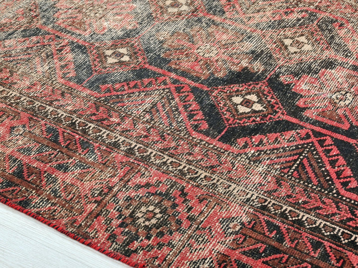 a red and black oriental rug on a wooden floor