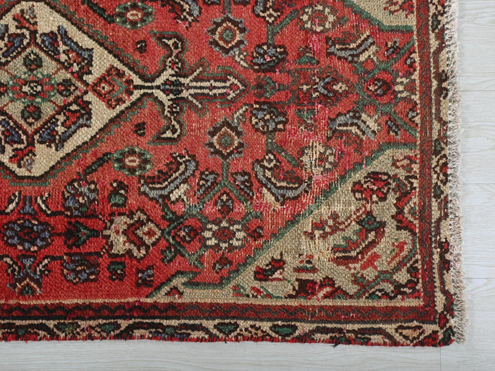a red rug with a design on the middle of it