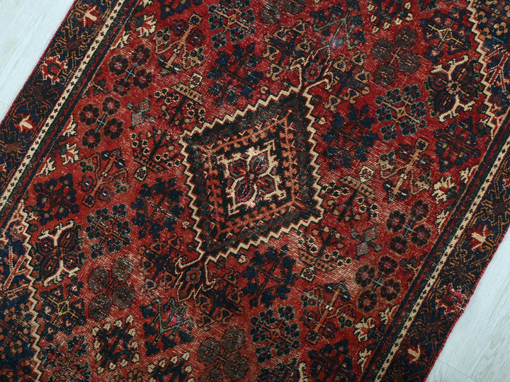 a red and black oriental rug on a wooden floor