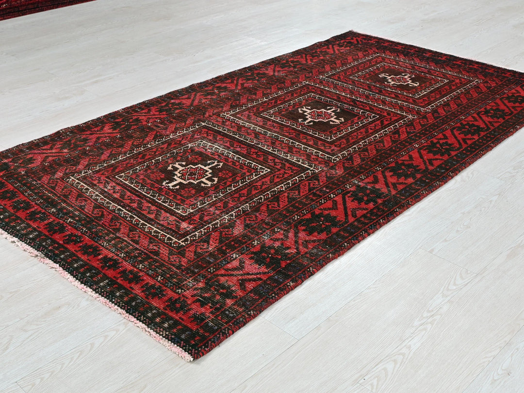 a red and black rug sitting on top of a white floor