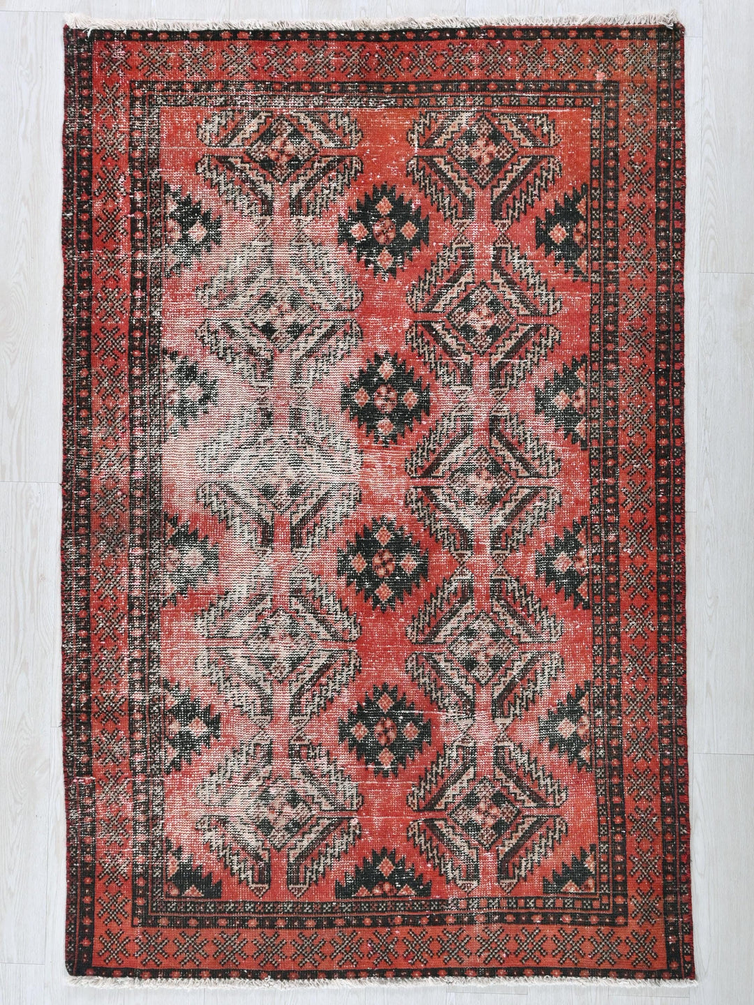 a red and black rug on a white floor