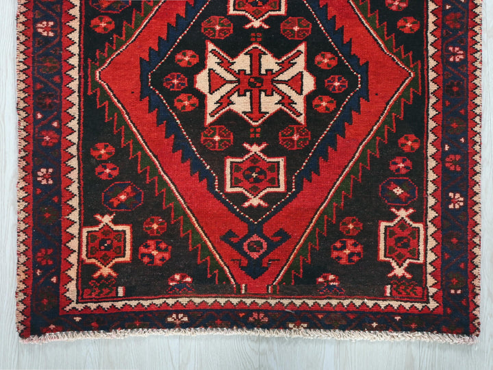 a red and black rug on a wooden floor