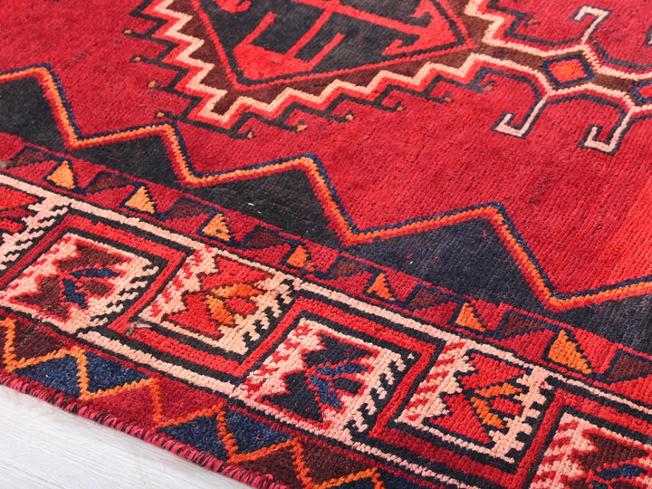 a close up of a red rug on a wooden floor