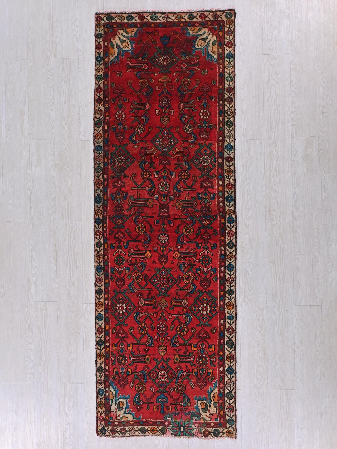 a red rug with a blue border on a white floor