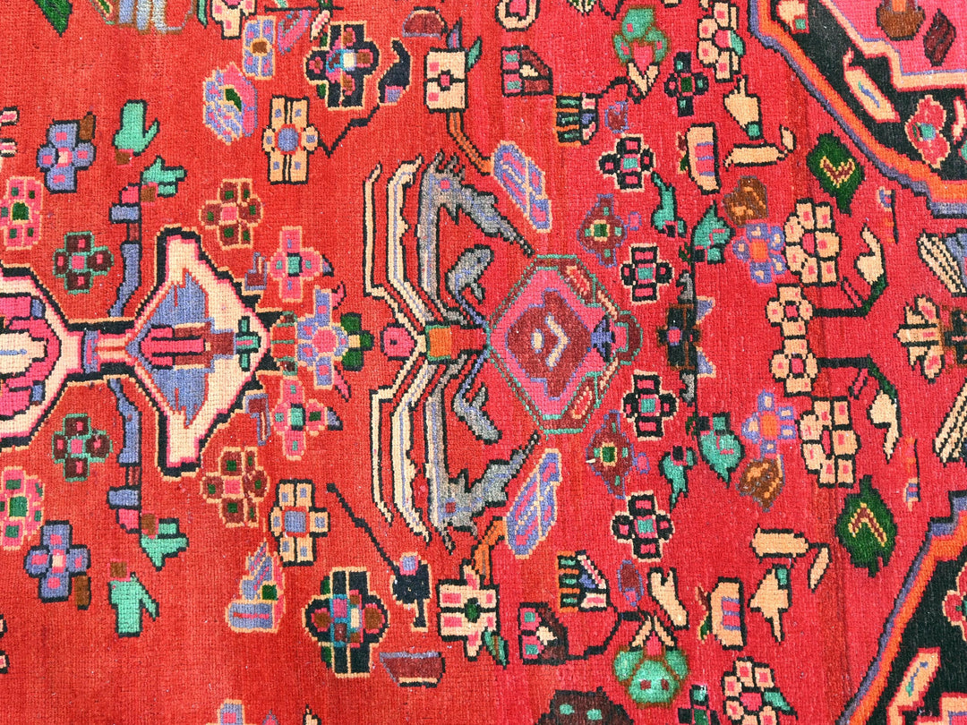 a red oriental rug with a colorful design