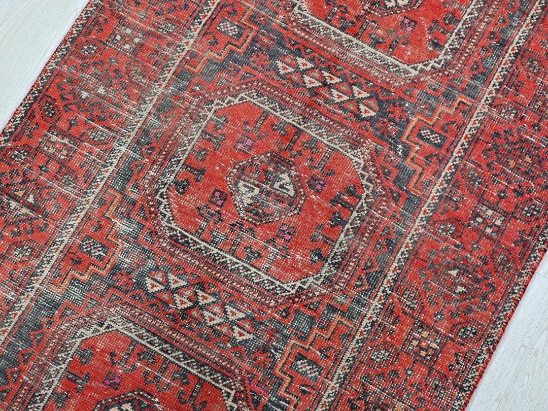 a red rug with a blue border on a white floor
