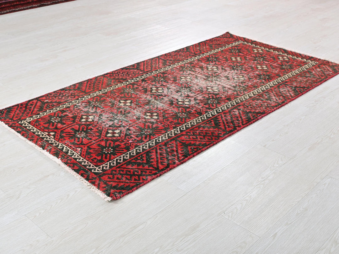 a red and black rug on a white floor