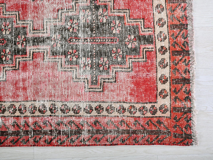 a red and black rug on a white floor