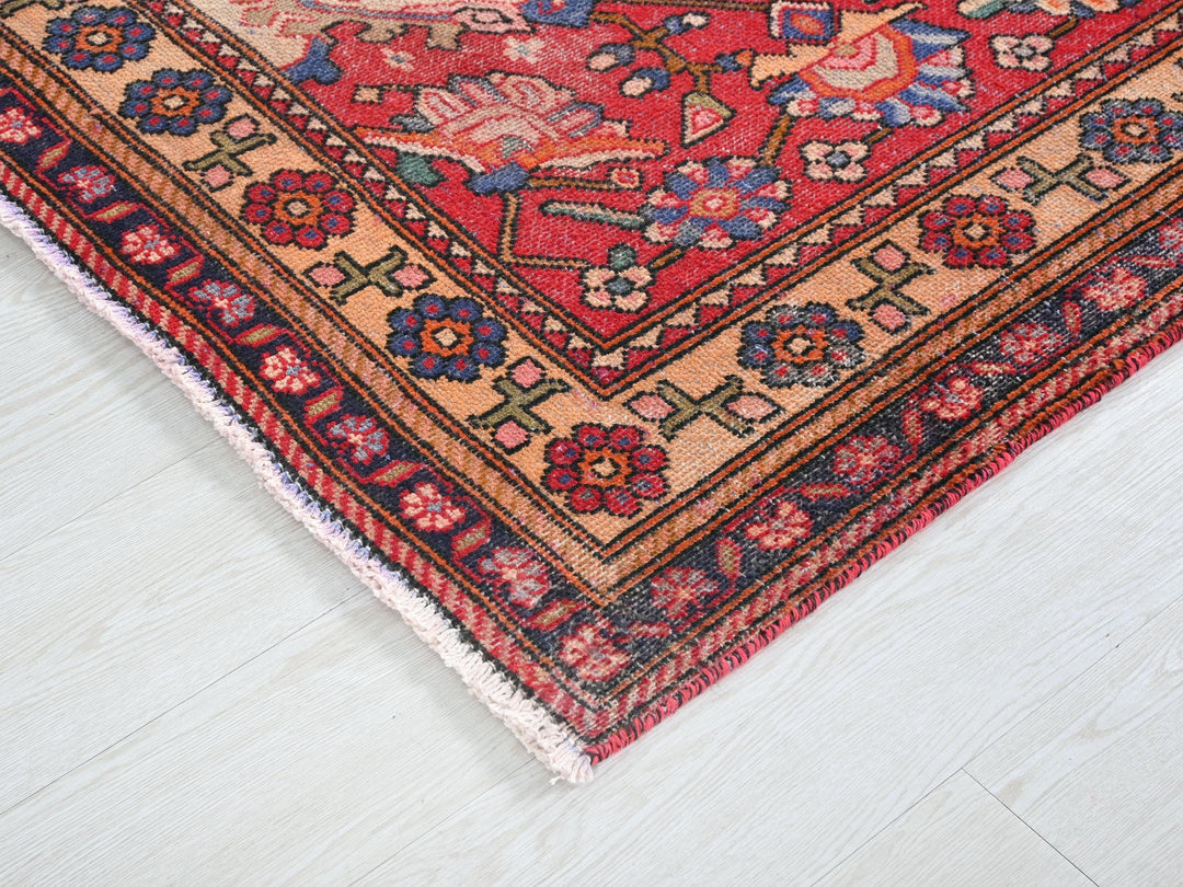 a red rug with a floral design on a white floor