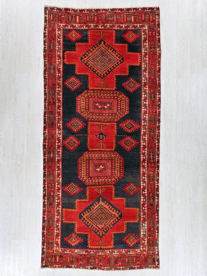 a red and black rug hanging on a wall