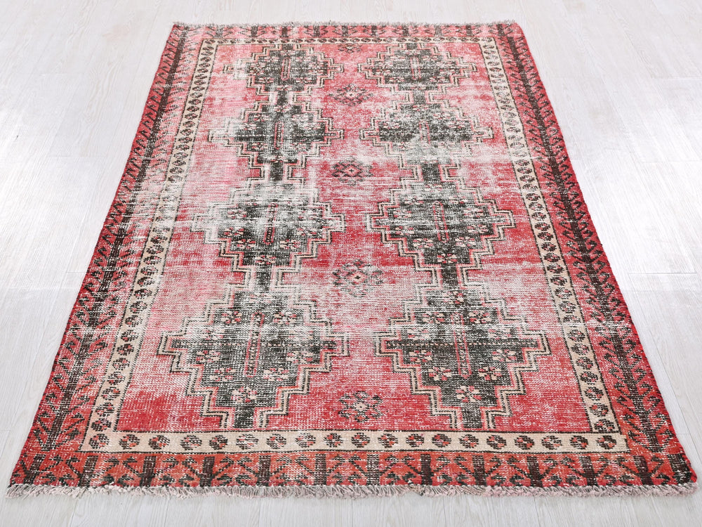 a red and black rug on a white floor