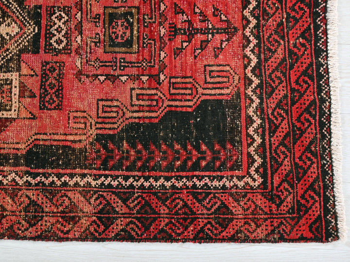 a red and black oriental rug on a white surface
