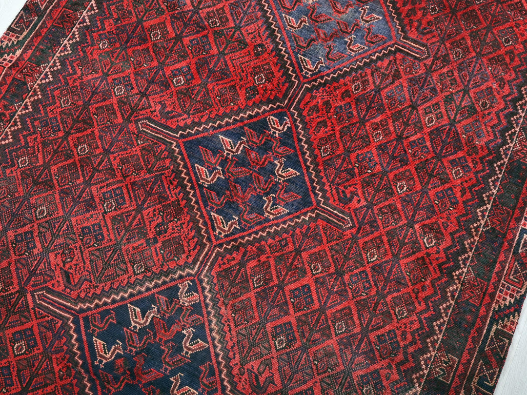 a red and blue oriental rug on a white surface