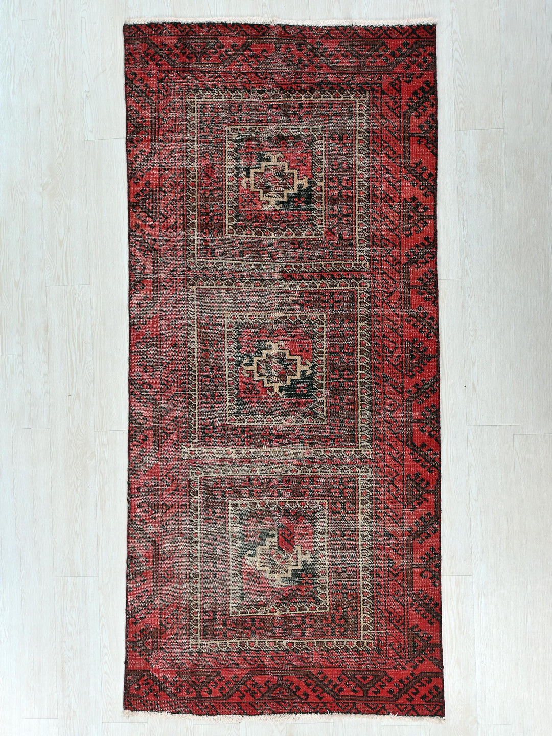 a red and black rug on a white floor