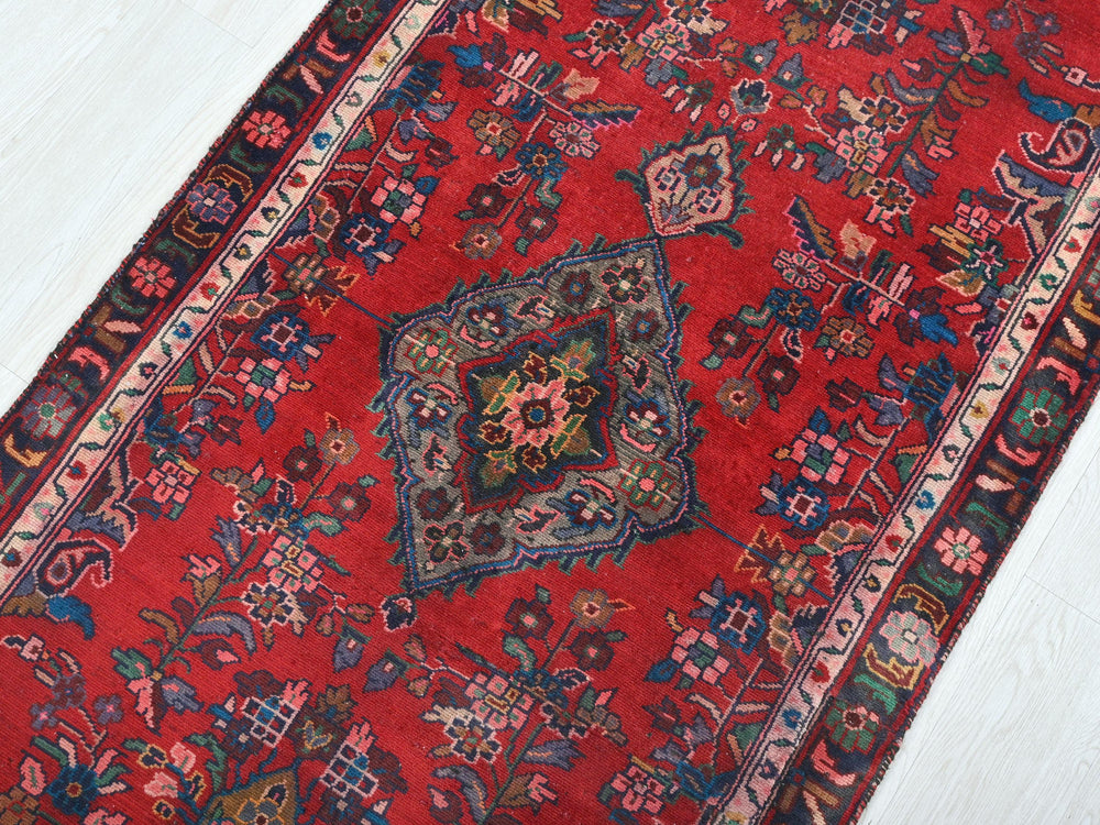 a red oriental rug on a white wooden floor