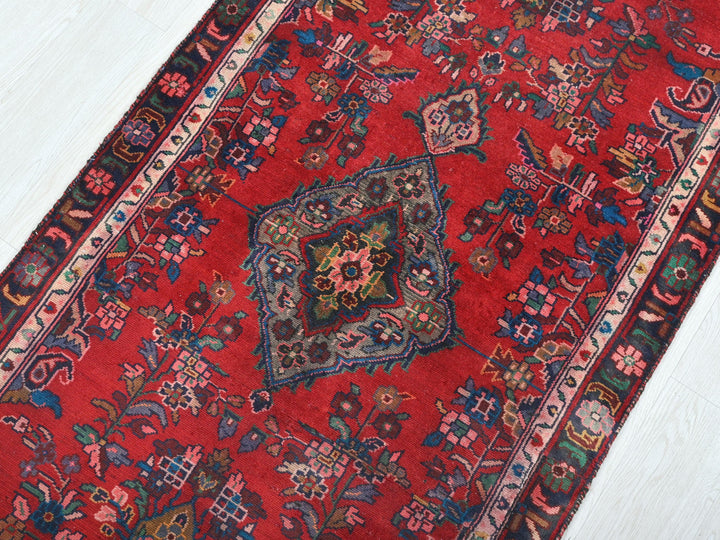 a red oriental rug on a white wooden floor