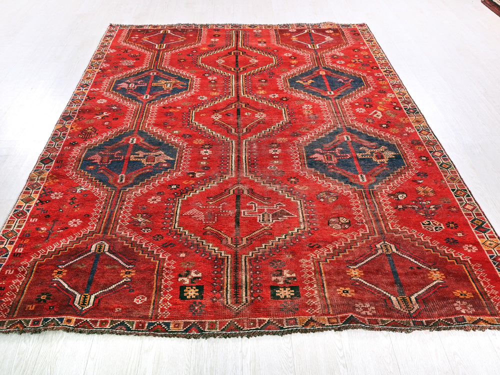 a red rug with a blue border on a white floor