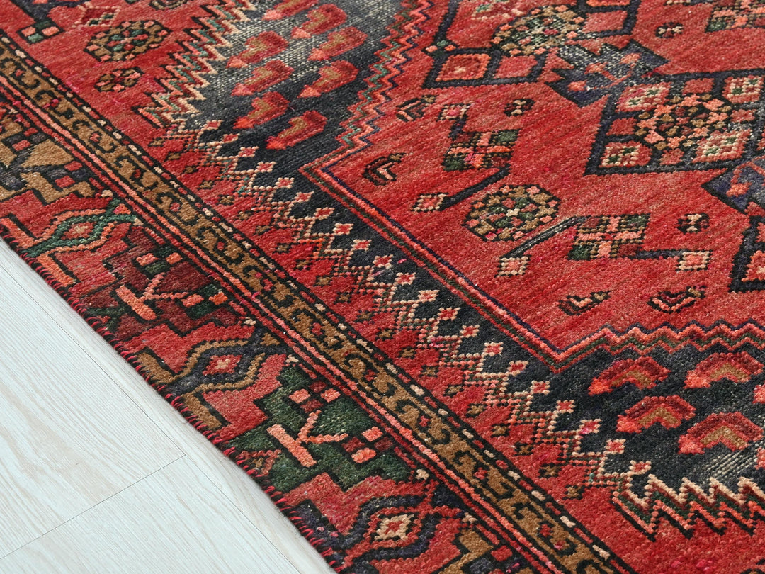 a red oriental rug on a white wooden floor