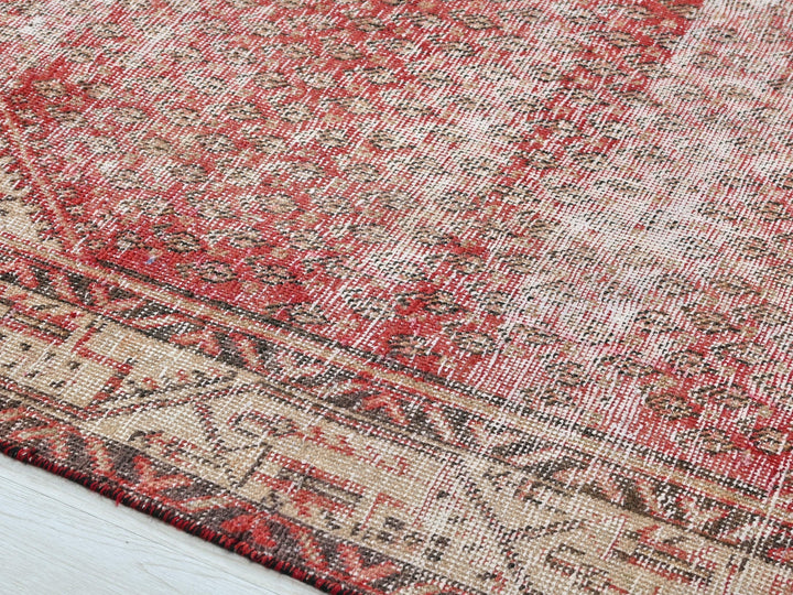 a red and beige rug on a wooden floor