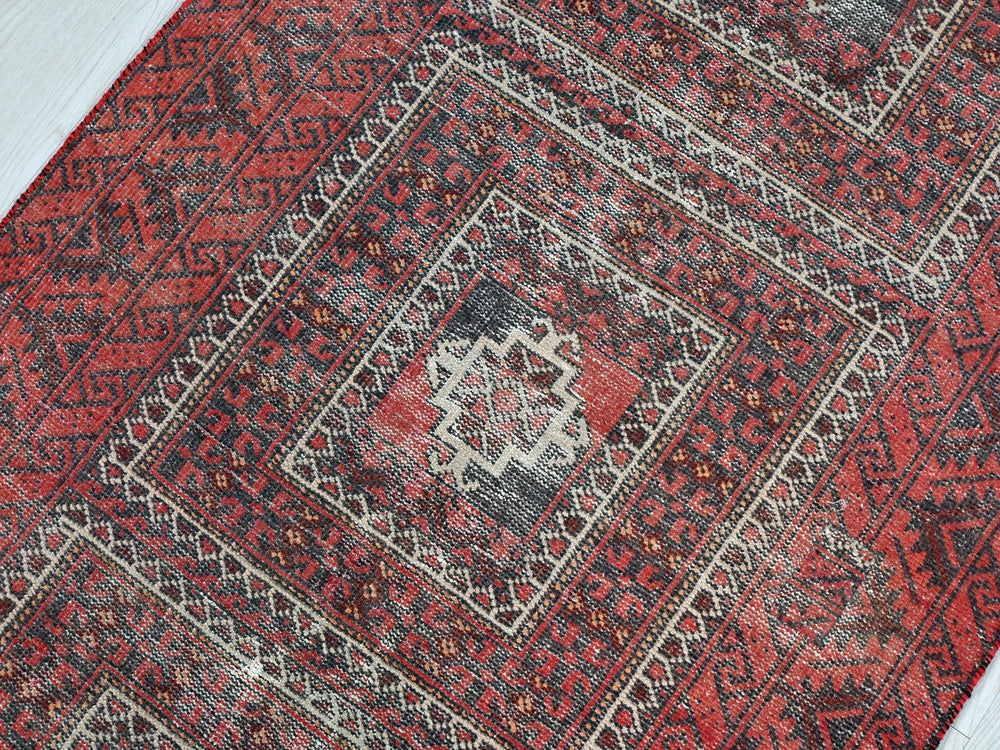 a red and black rug on a wooden floor