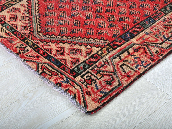 a red and black oriental rug on a white wooden floor