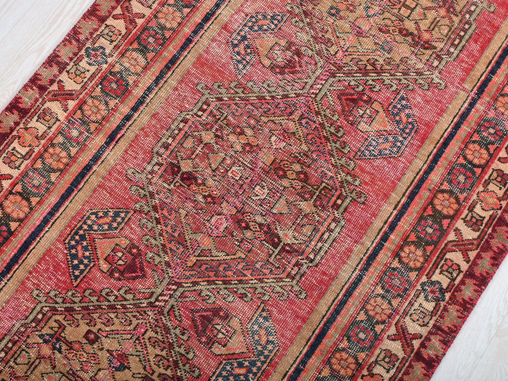 a red oriental rug on a white wooden floor