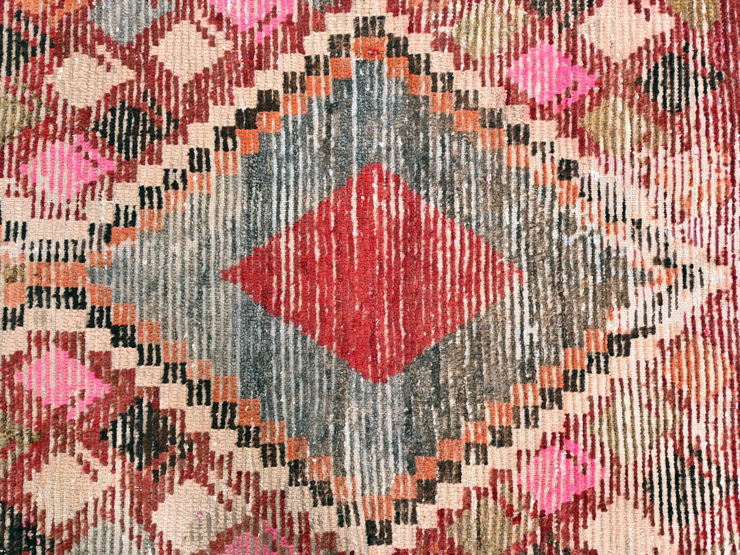an old rug with a red diamond in the middle