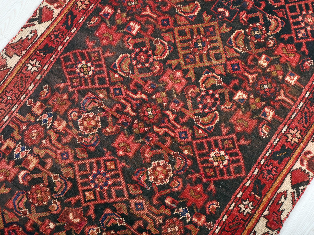 a red and black oriental rug on a white floor