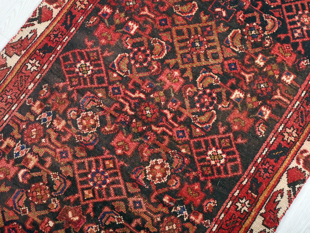 a red and black oriental rug on a white floor