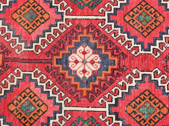 a red and blue rug with a diamond pattern