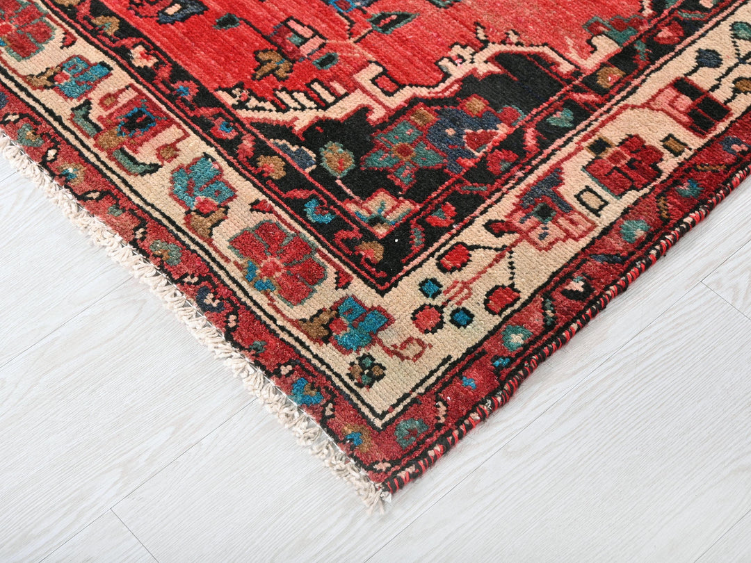 a red oriental rug on a white wooden floor