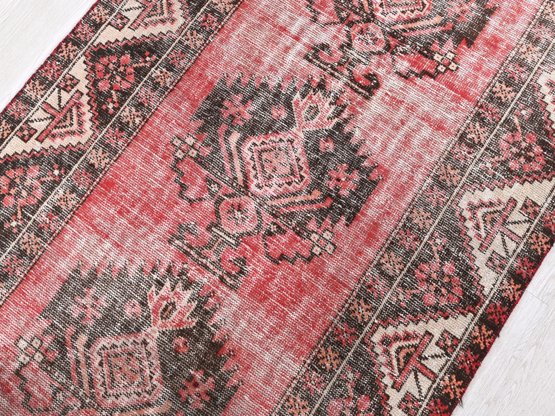 a red and black oriental rug on a white wooden floor